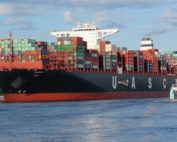 Ein Containerschiff fährt in einen Hafen.