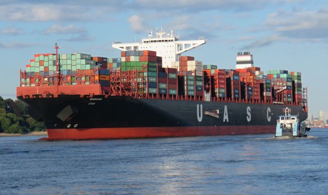 Ein Containerschiff fährt in einen Hafen.