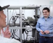 Interviewsituation mit einem Kraftstoff-Prüfstand im Hintergrund