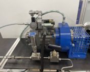 On a test bench there is a metal fuel pump with hoses for the supply and removal of fuel.