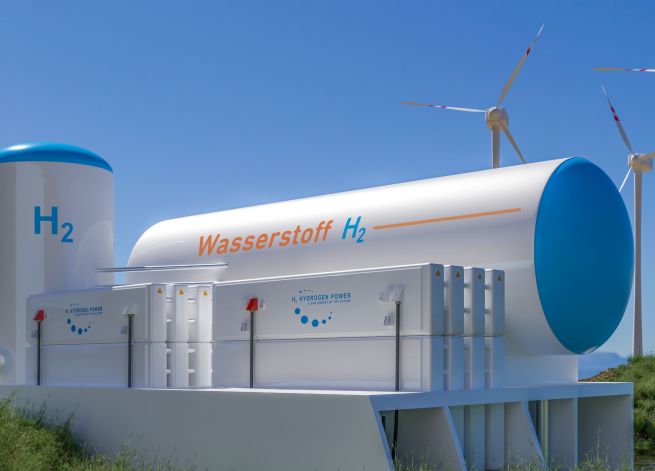 Windräder, Wasserstofftanks und Elektrolyseure vor blauem Himmel