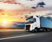 Ein Lastwagen auf einer Straße in den Bergen mit Sonnenuntergang.