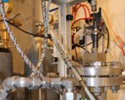 A blach GDI-injector in a test rig with pipes, hoses and cables.